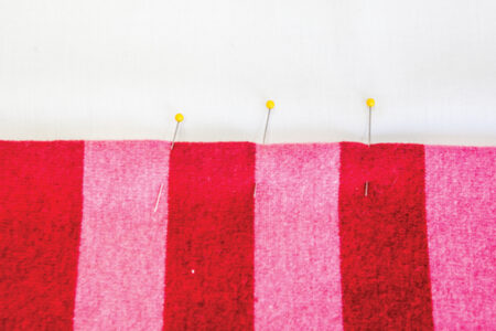 pins on the end of pink and red striped fabric